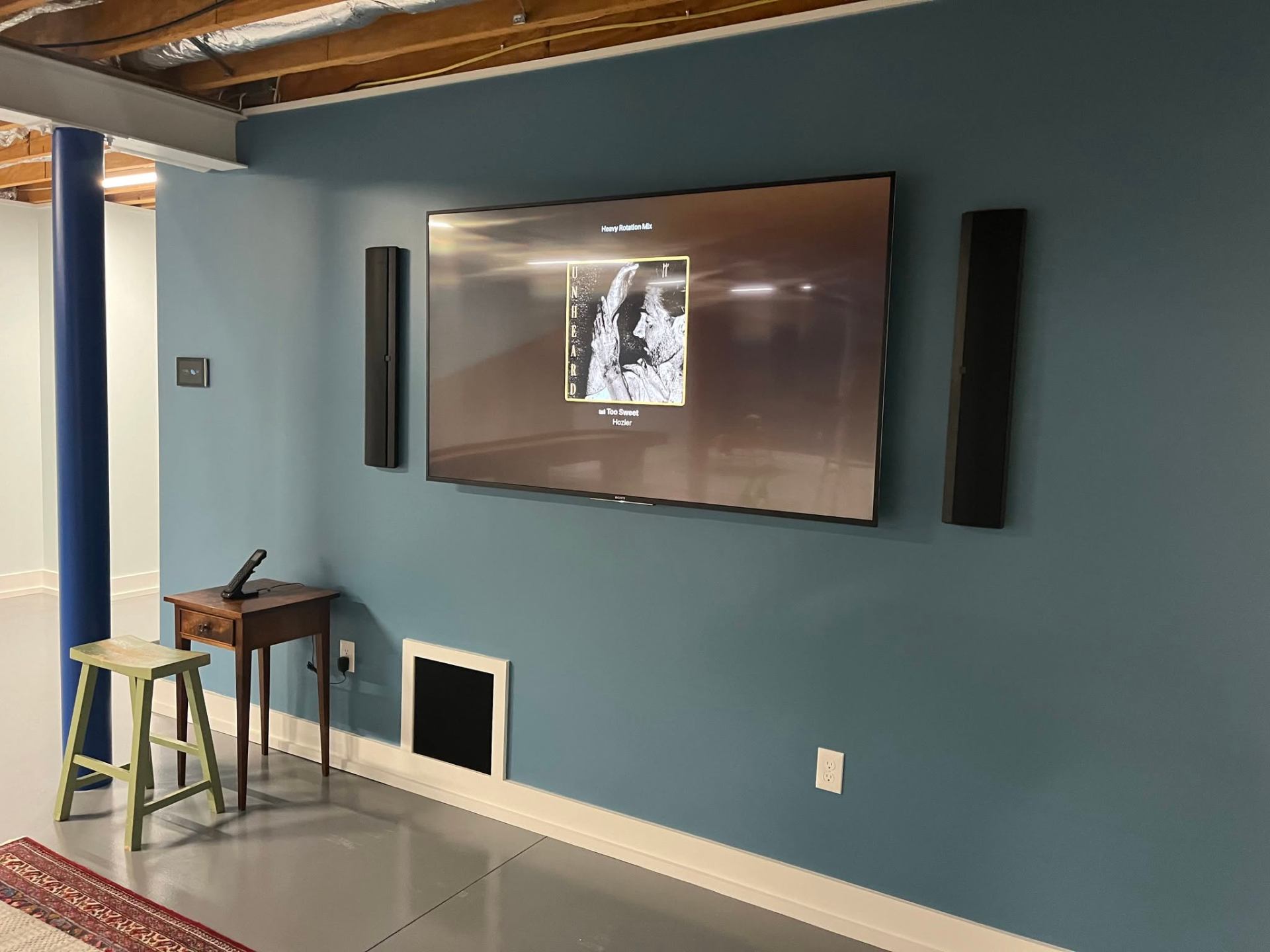 On-wall speakers with hidden subwoofer enclosure in listening room